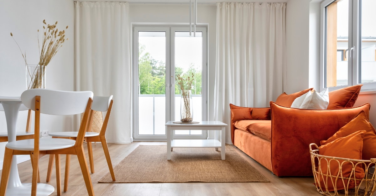 modern living room with orange couch chairs table during day time