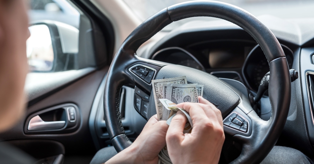 man in his car count us money bills for pay