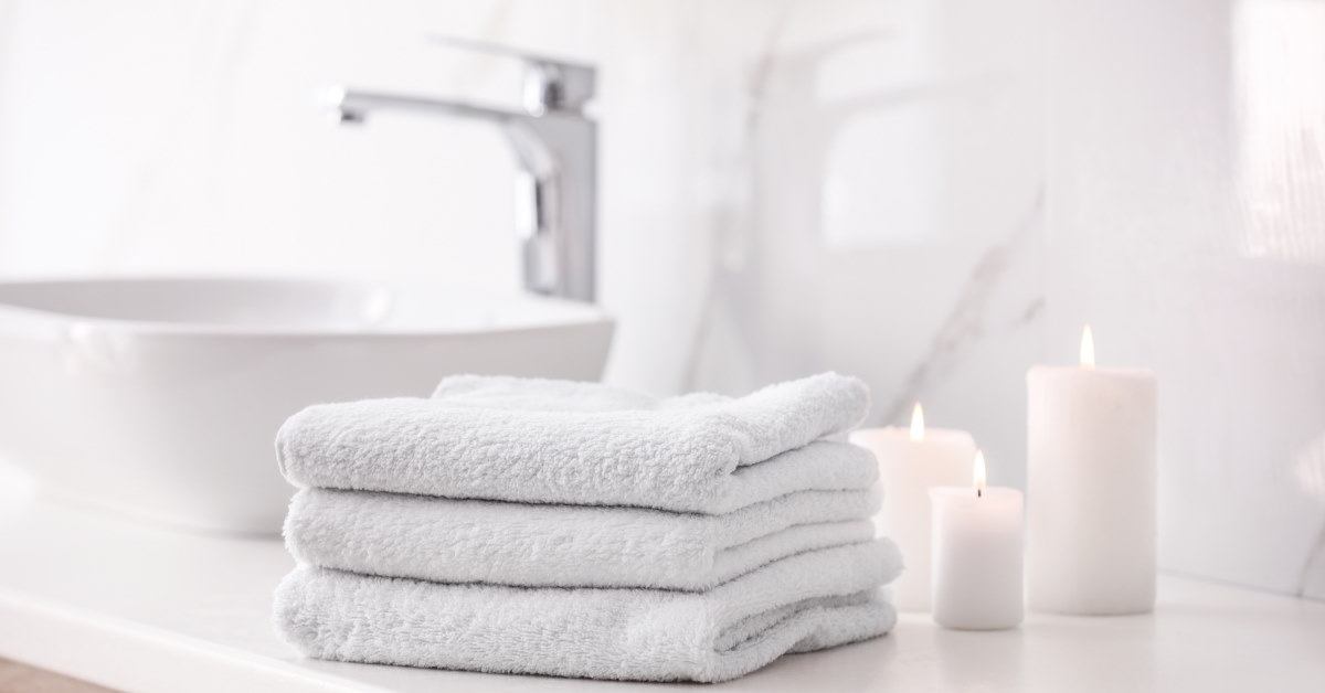 white towels placed on marble top next to candles in bathroom