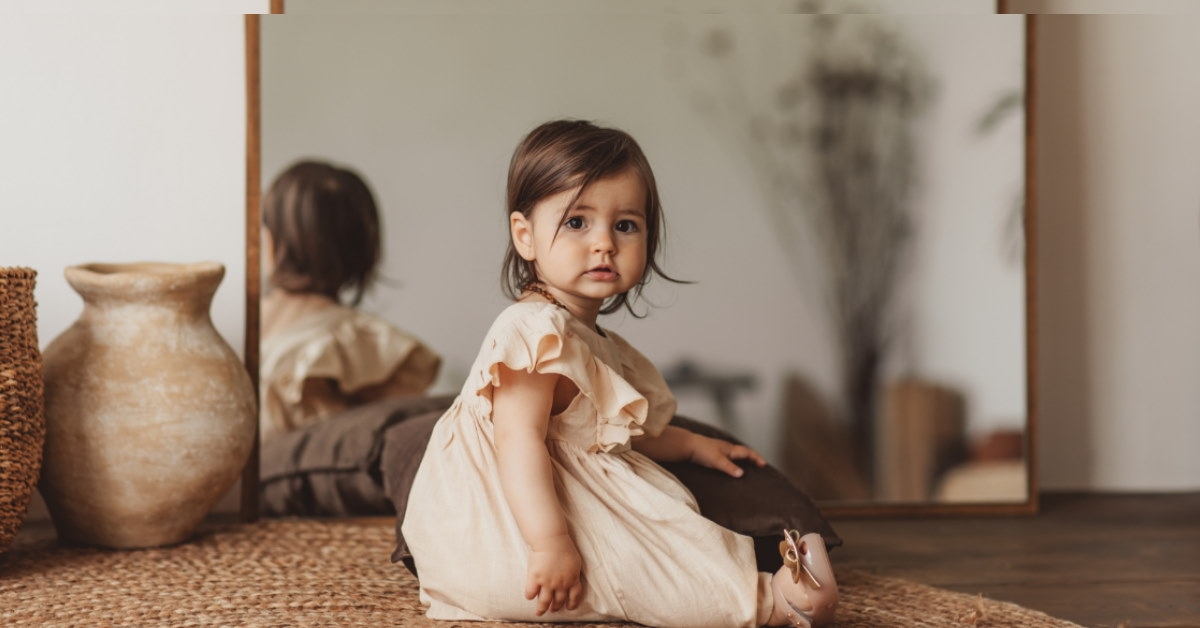 toddler sitting on rug with huge mirror in background