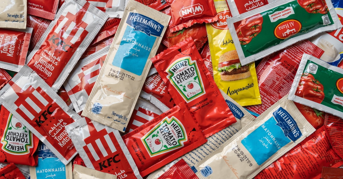 sachets of tomato ketchup and mayonnaise scattered on table