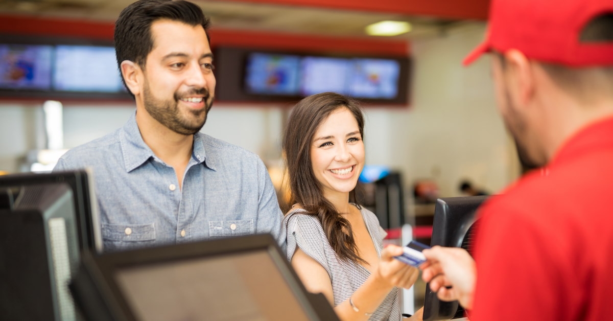 woman standing with her partner in cinema paying for tickets