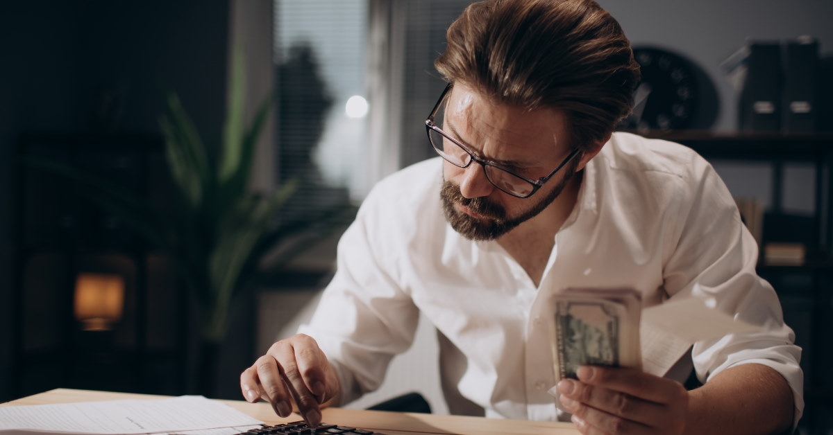 mature man counting money using calculator