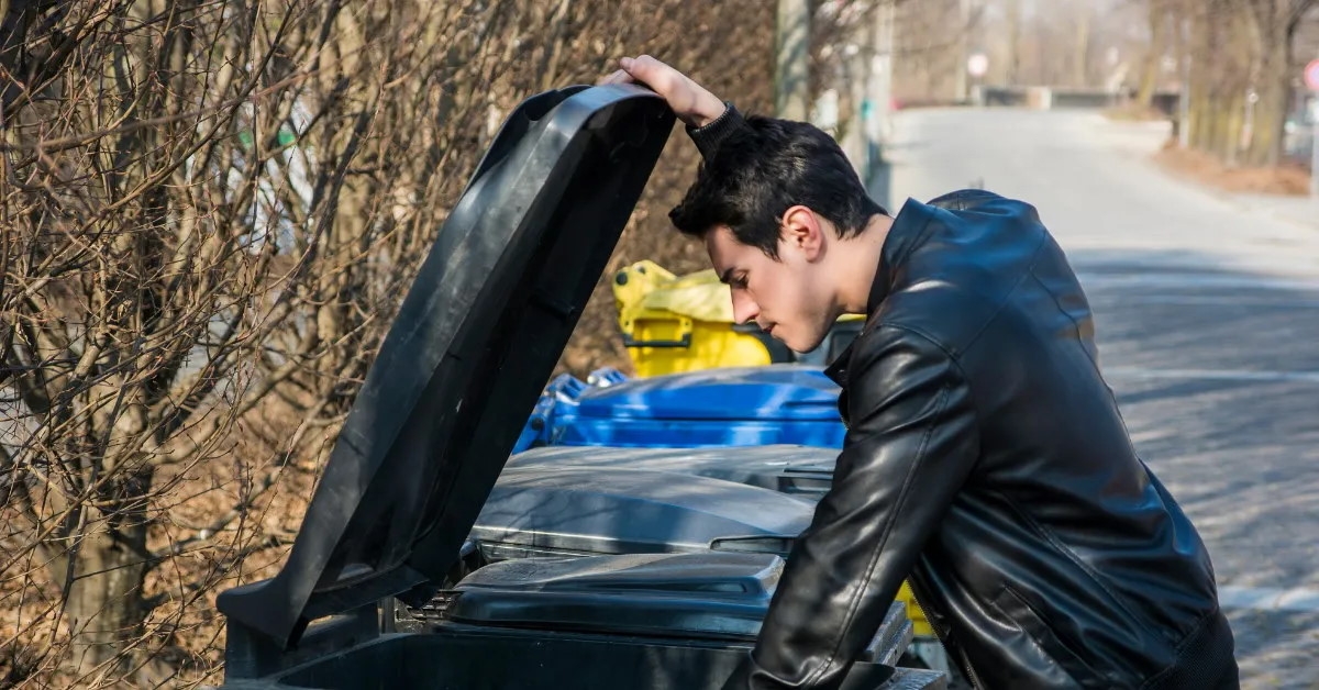 young man in black jacket disposing trash outdoor