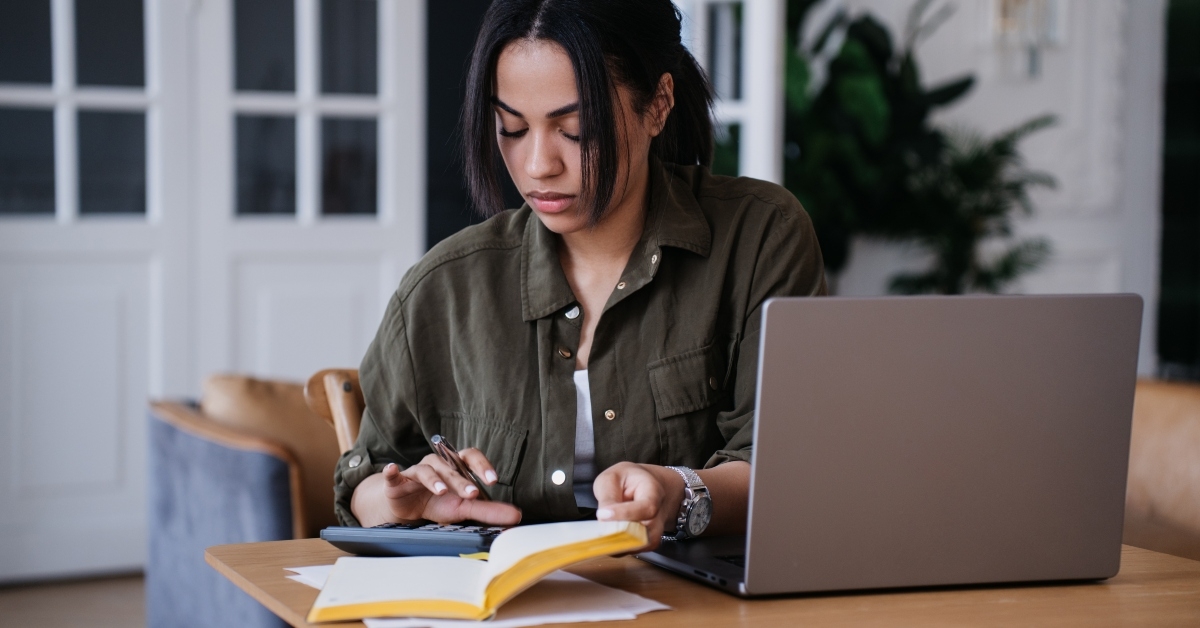 young woman uses calculator to count profit of her business
