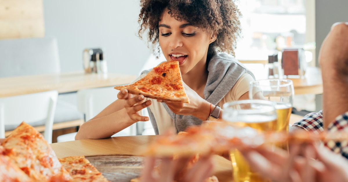 african american woman sitting in cafe eating pizza at table