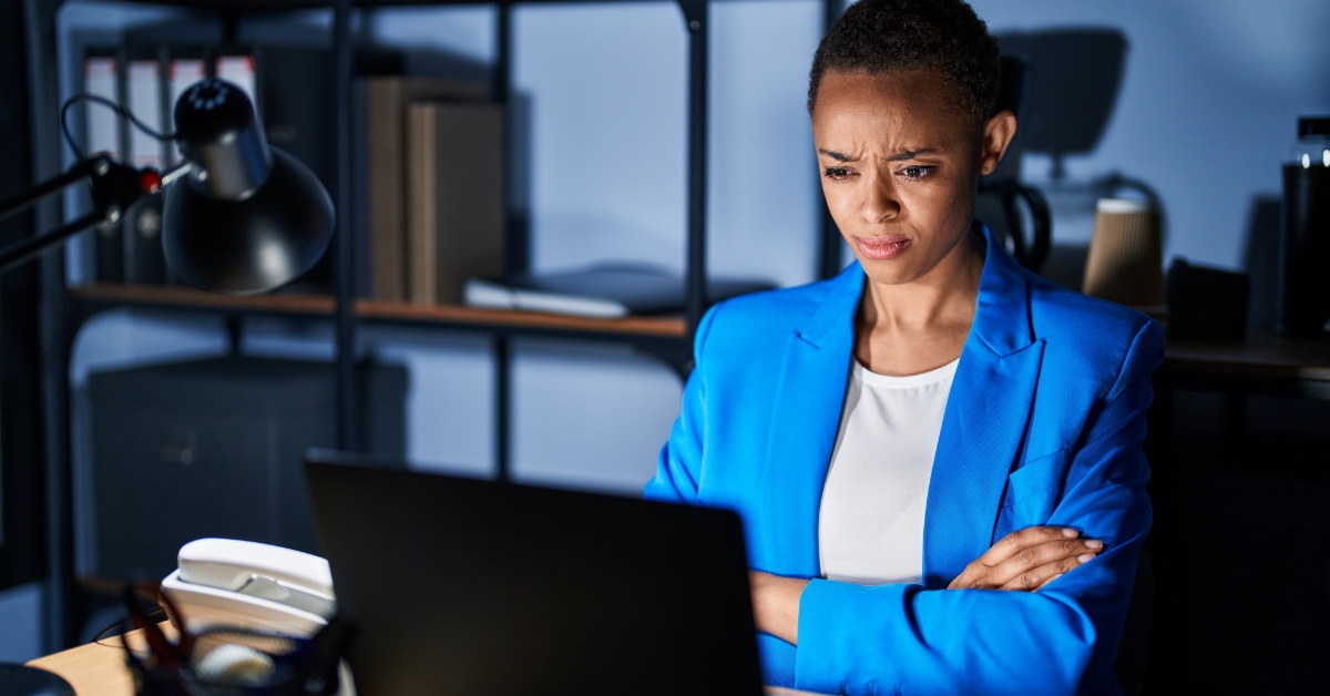african american woman folding hands frowning at laptop screen 