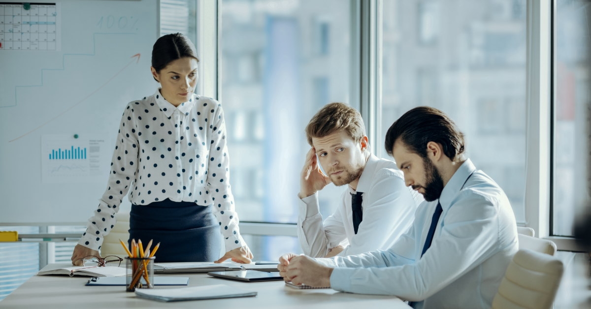 female boss standing in office scolifing employes