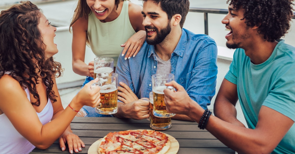 group of friends enjoying pizza and champagne on an outdoor table
