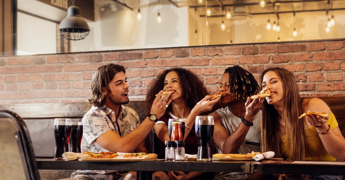 friends sharing pizza and drinks at a table 