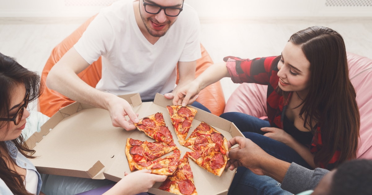 friends sitting on bean bags at floor eating pizza out of the box