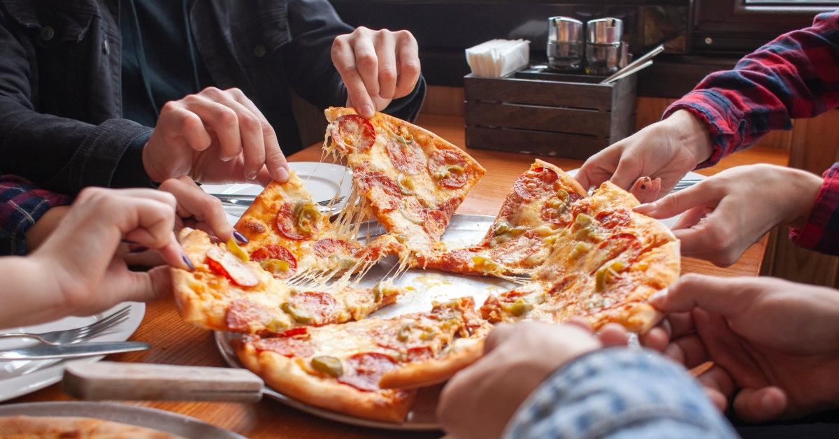 group of friends in restaurent picking out pizza slices from the table