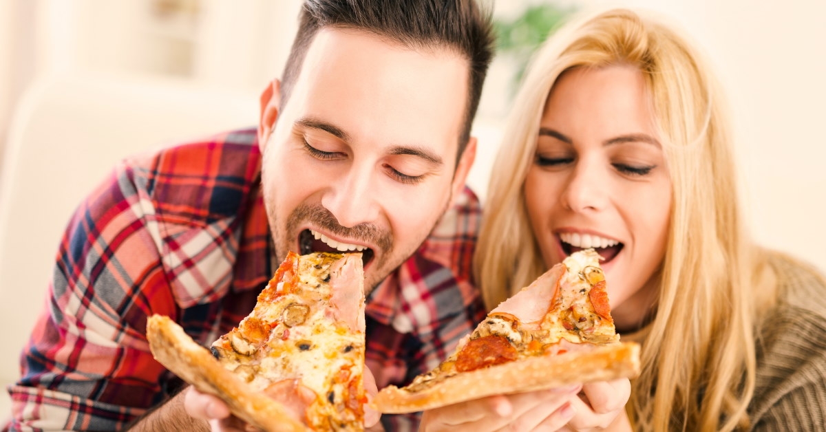happy couple having pizza slices at home