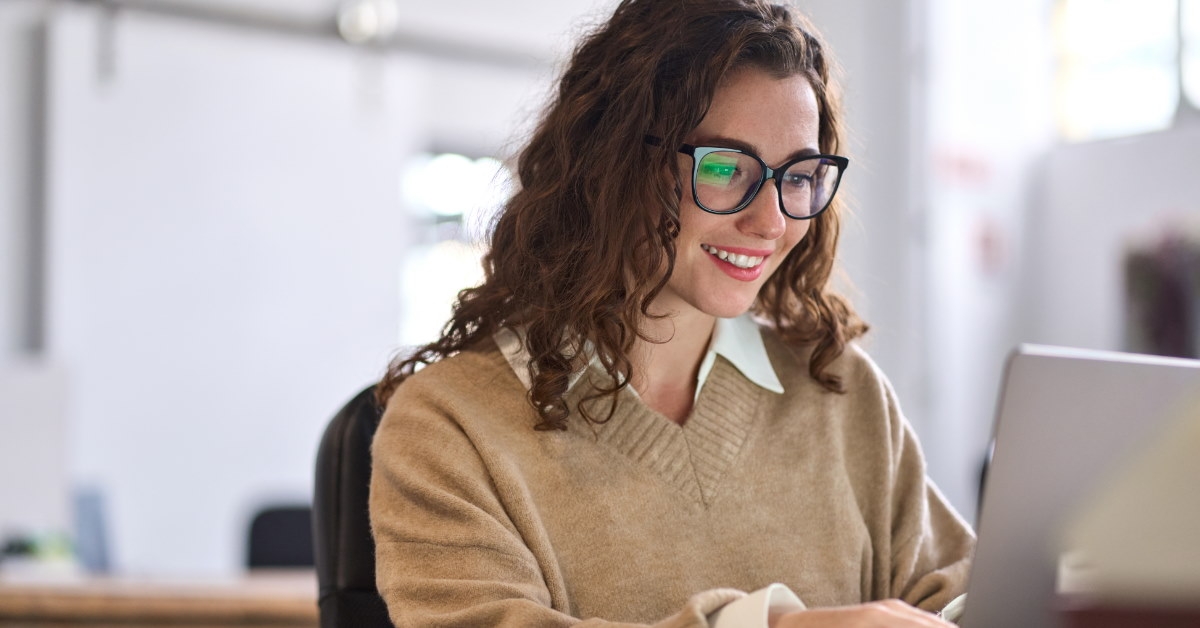 beautiful happy woman sitting at table using laptop for work at office