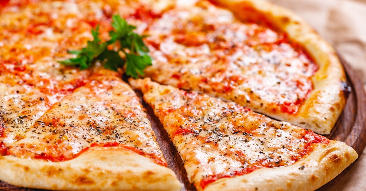 italian margaritta pizza on wooden cutting board 