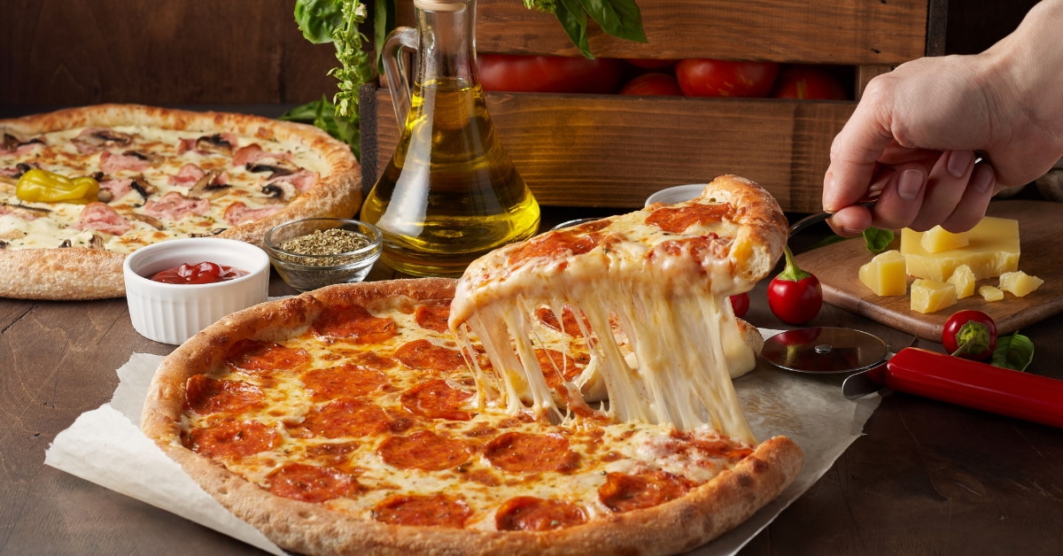 man using a slicer to pull out a pizza slice with melted cheese