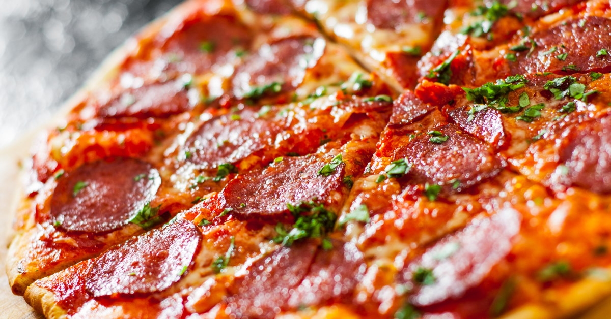 pepperoni pizza with cheese and tomato sauce, topped with aromatic basil leaves