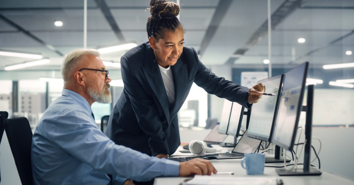 female manager explaining work on monitor to senior businessman