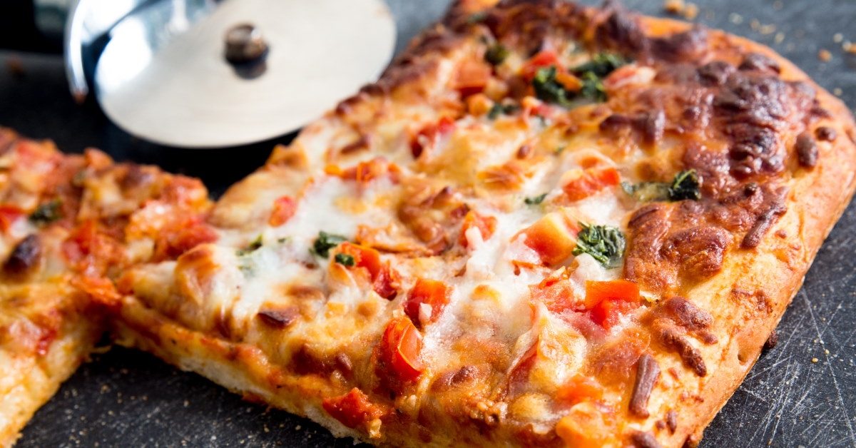 square slices of margaritta pizza on cutting board