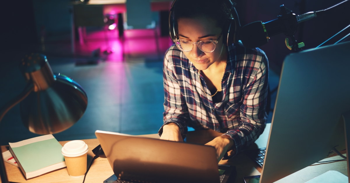 woman waring headset working on laptop late at night 