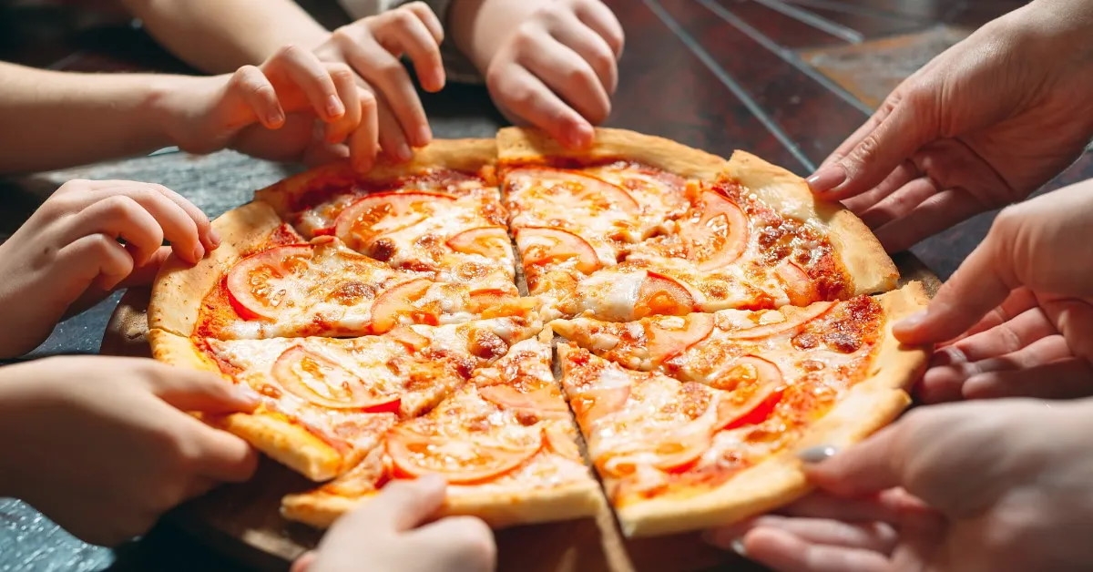family members sitting together pulling apart pizza slices