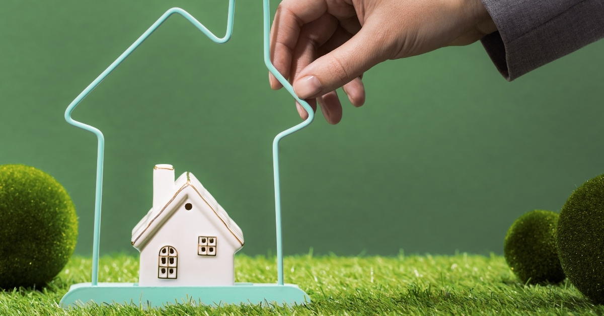 hand with small house within bigger house frame