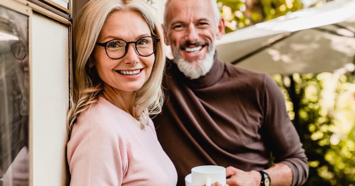pleased senior couple smiling with cups of coffee
