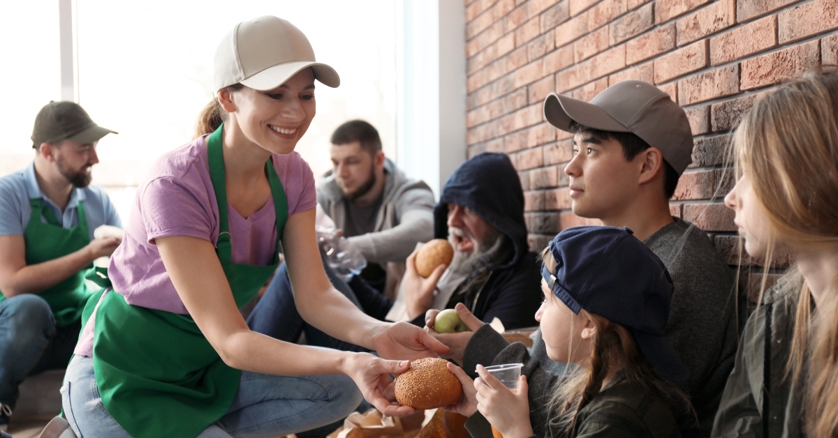 volunteers giving food to poor people indoors