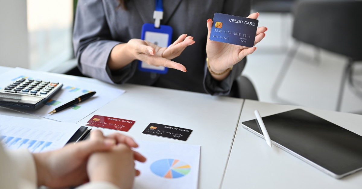 female accountant in suit explaining the benefits of new credit card to female client across the table in bank