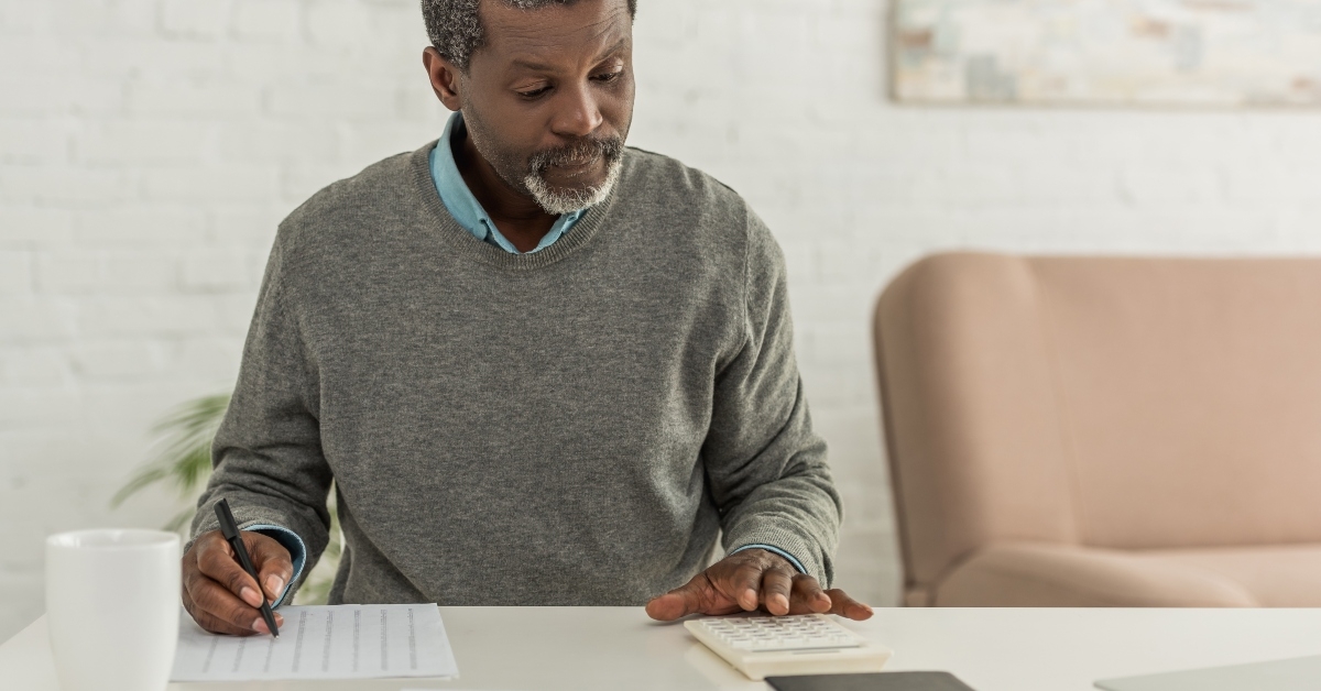 man calculating expenses while writing in utility bill
