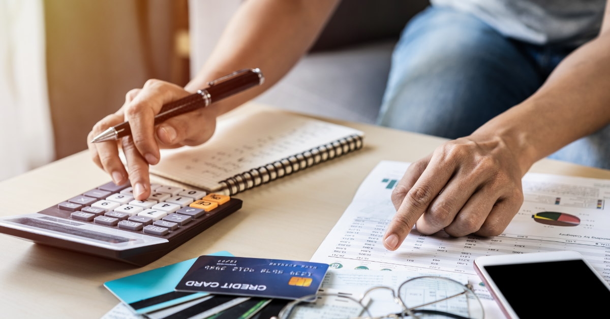 woman sitting with cards bills and smartphone calculating utility bills using calculator