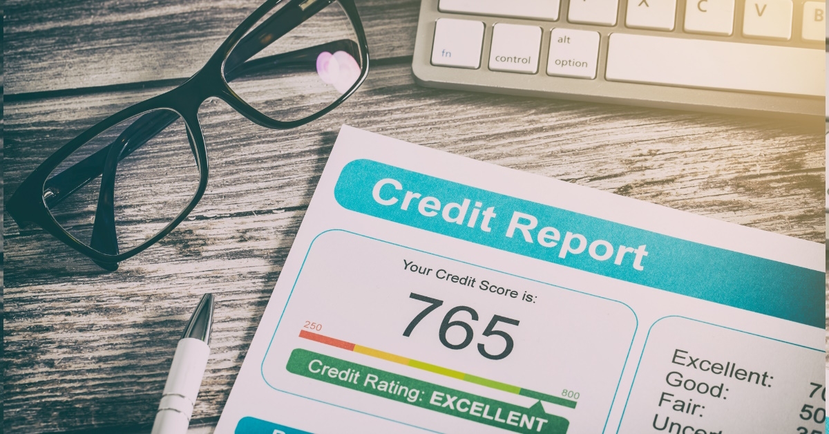 credit report placed on wooden table alongside pen glasses and keyboard