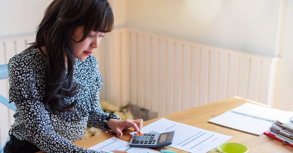 woman calculating finance while reviewing bills using calculator