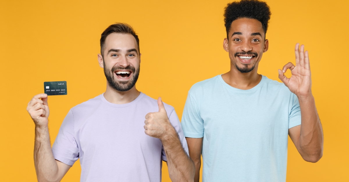 two male friends doing thumbs up and okay sign while holding card 
