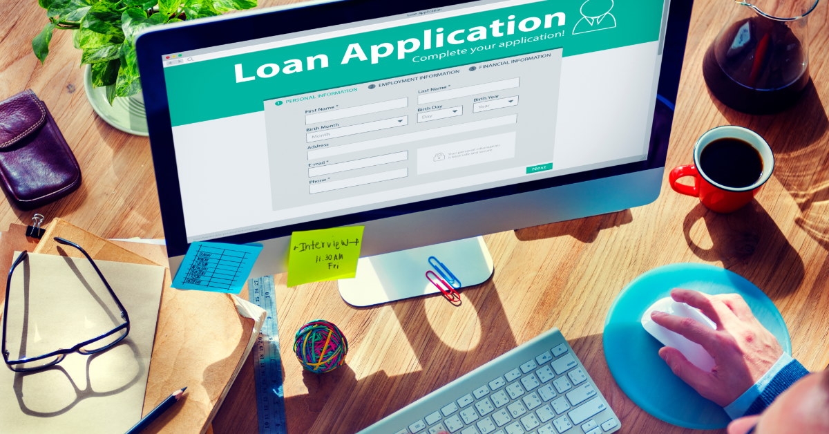 businessman sitting at table using desktop computer with loan application form