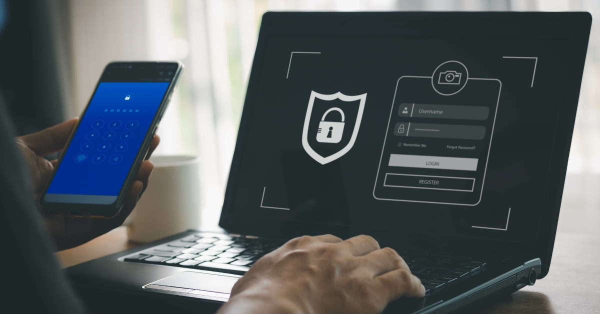 man holding smartphone giving login credentials on laptop