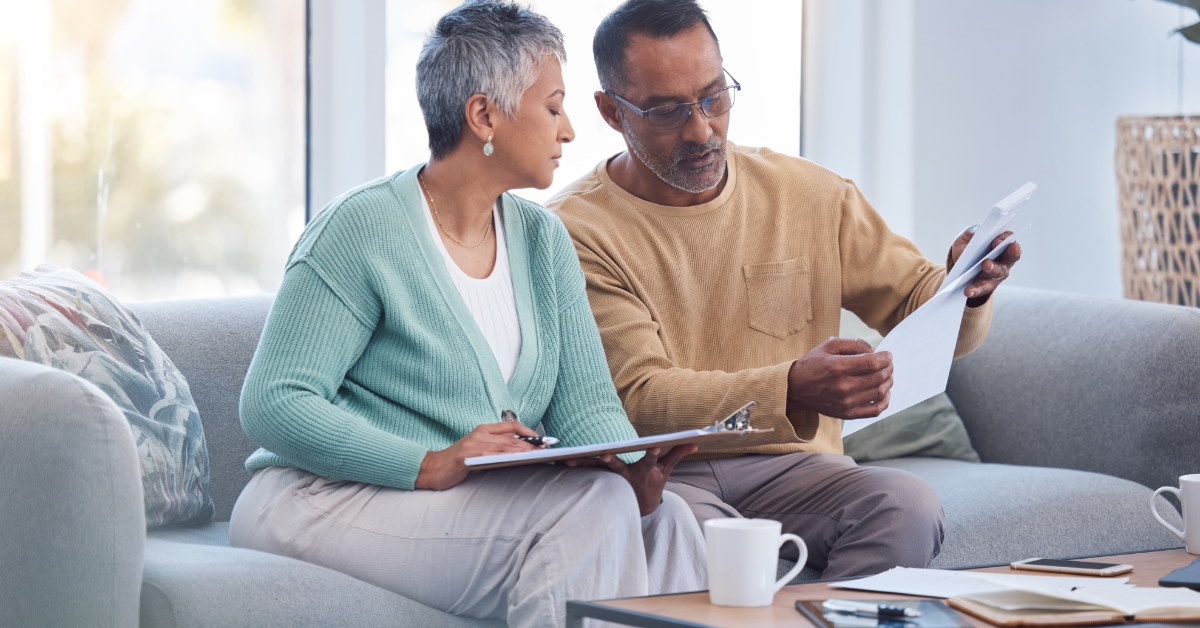 African American seniorcouple sitting at table reviewing bills at home