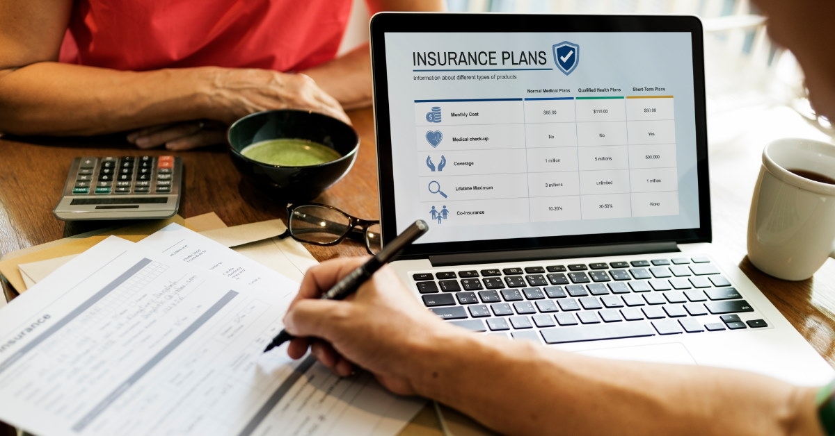 life insurance agent sitting at table with insurance plans on laptop