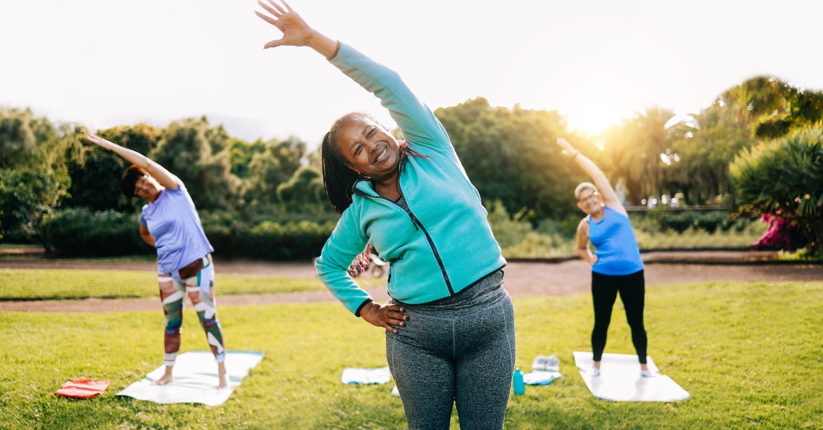 multi ethnic women doing exercise on mats at outdoor park during day time