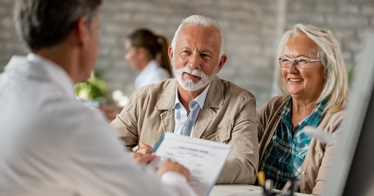 senior couple sitting in front of male insurance agent discussing policies to buy