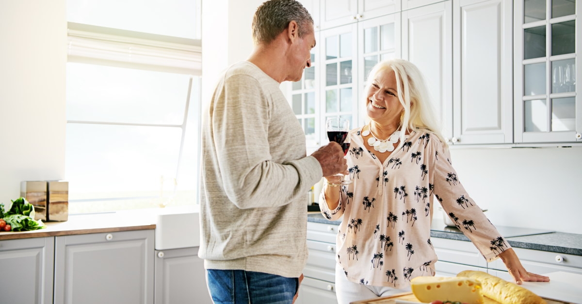 Senior couple standing in kitchen working on preparation of meal