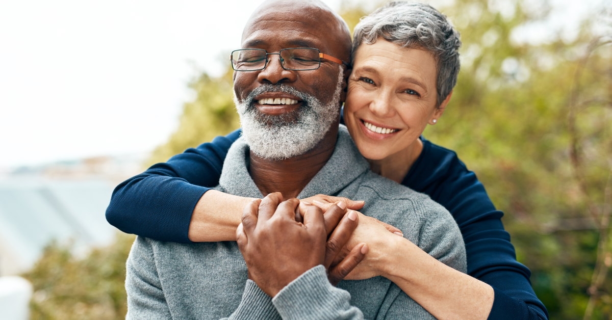 senior multi ethnic couple hugging each other while spending quality time at park