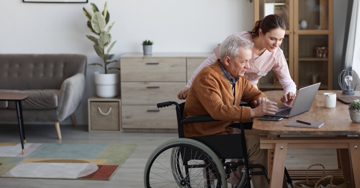  senior man in wheelchair using laptop at retirement home