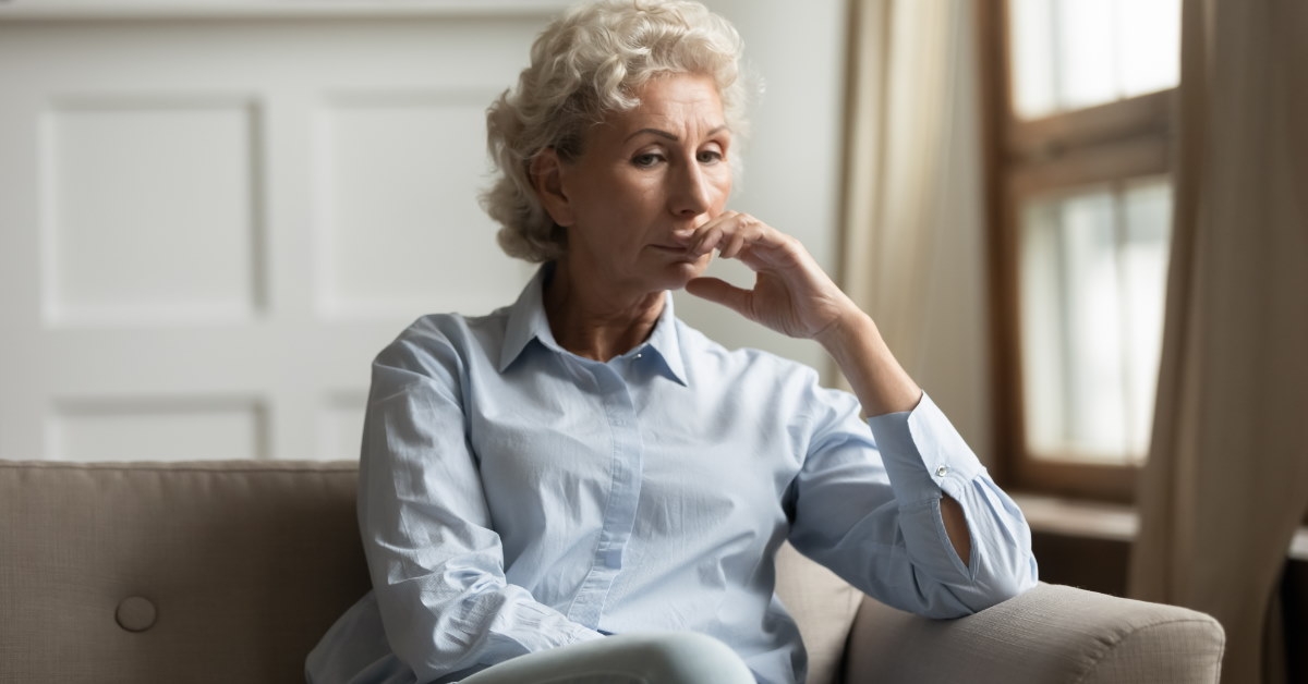 unhappy senior woman sitting on couch thinking 