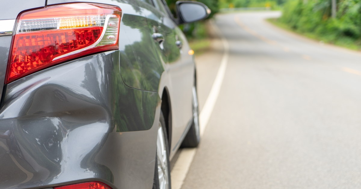 grey car standing on road after having dent on rear bumper
