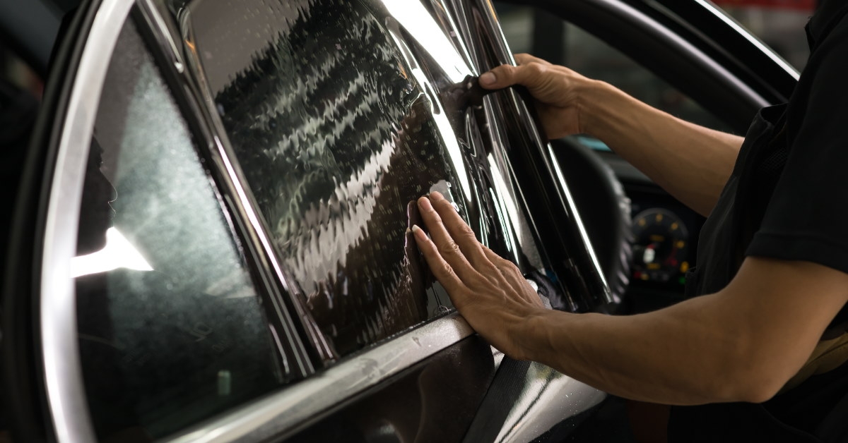 mechanic applying window tints in black color to car windows
