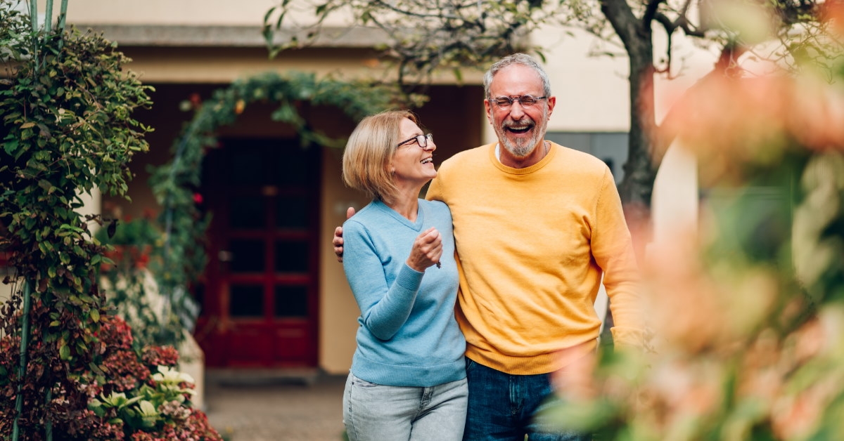 senior couple laughing while hugging each other outside new home