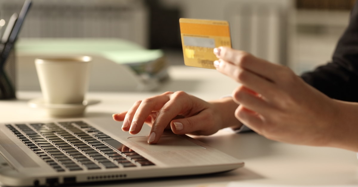woman using laptop for online payment while holding card