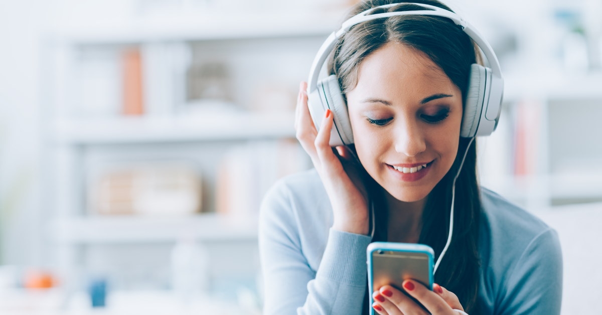 woman holding smartphone while wearing headset for listening to music