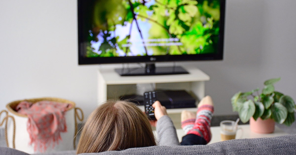 woman sitting on couch at home watching tv 